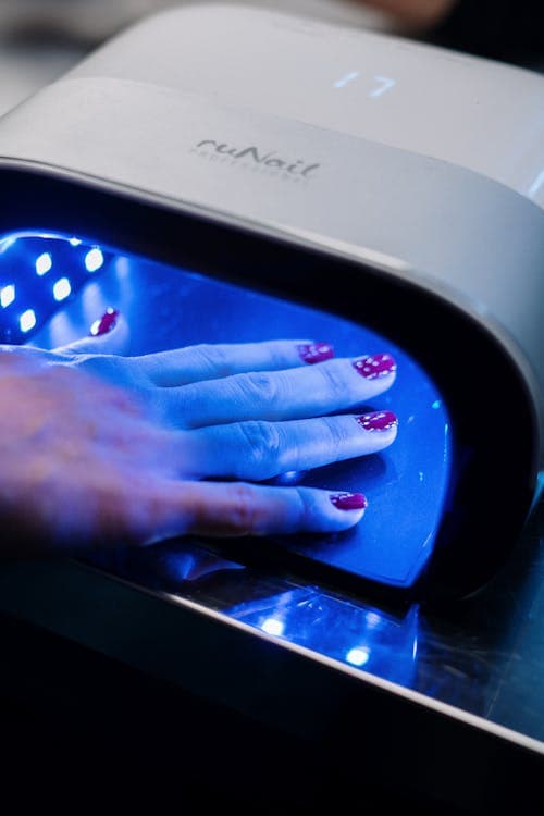 Red nails curing under UV lamp in professional salon